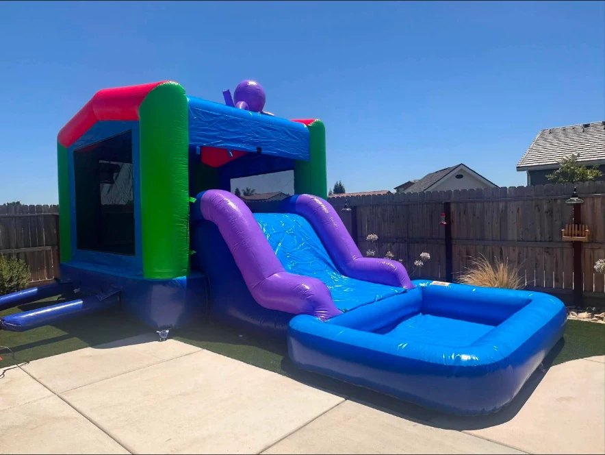 Blue, green and purple inflatable combo bounce house with a water slide and splash pool